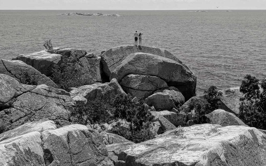 couple standing on rocky beach looking out at the water